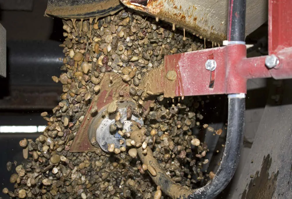 TDR moisture probe installed at a conveyor discharge with aggregate passing over the sensor face